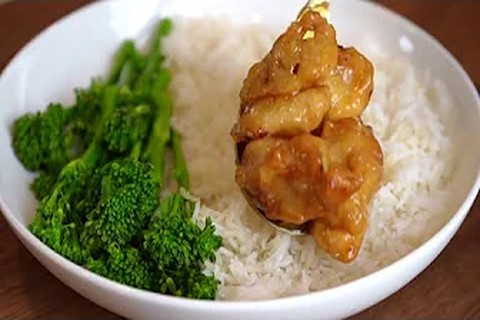 Plating the finished copycat Panda Express orange chicken with sesame seeds