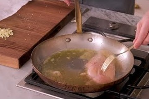 Searing chicken breasts in olive oil and butter in a skillet until golden brown