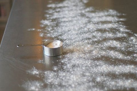 Sprinkling cinnamon and sugar over melted butter on rolled dough