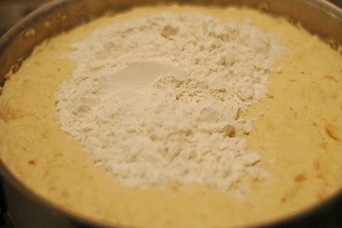 Rolling out cinnamon roll dough into a large rectangle on a floured surface