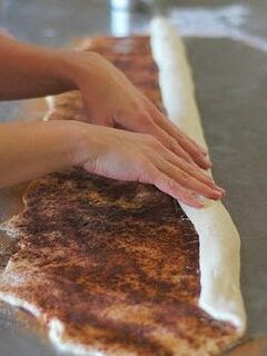 Slicing the cinnamon roll dough log into individual rolls