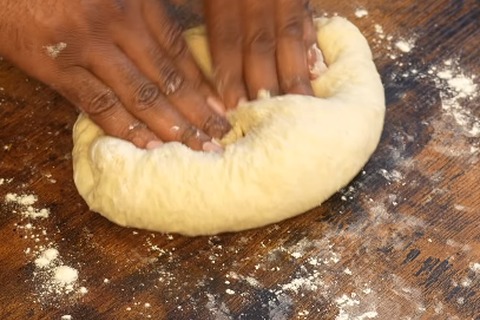Kneading smooth and elastic yeast dinner roll dough on a floured surface