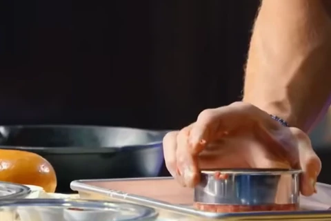 Pressing ground beef into a round mold for uniform Gordon Ramsay burger patties